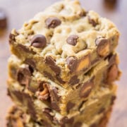 Stack of chocolate chip cookie bars on a wooden surface.