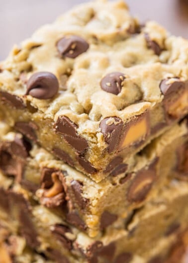 Stack of chocolate chip cookie bars on a wooden surface.