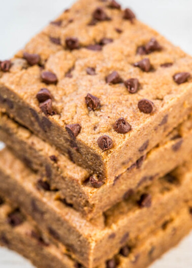 Stack of chocolate chip blondies on a wooden surface.