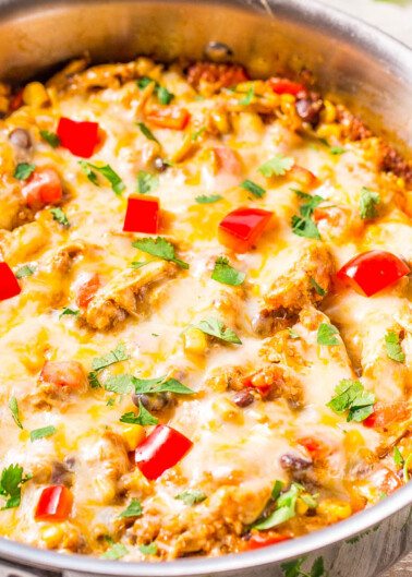 A skillet with a melted cheese-topped dish, garnished with diced tomatoes and fresh cilantro.