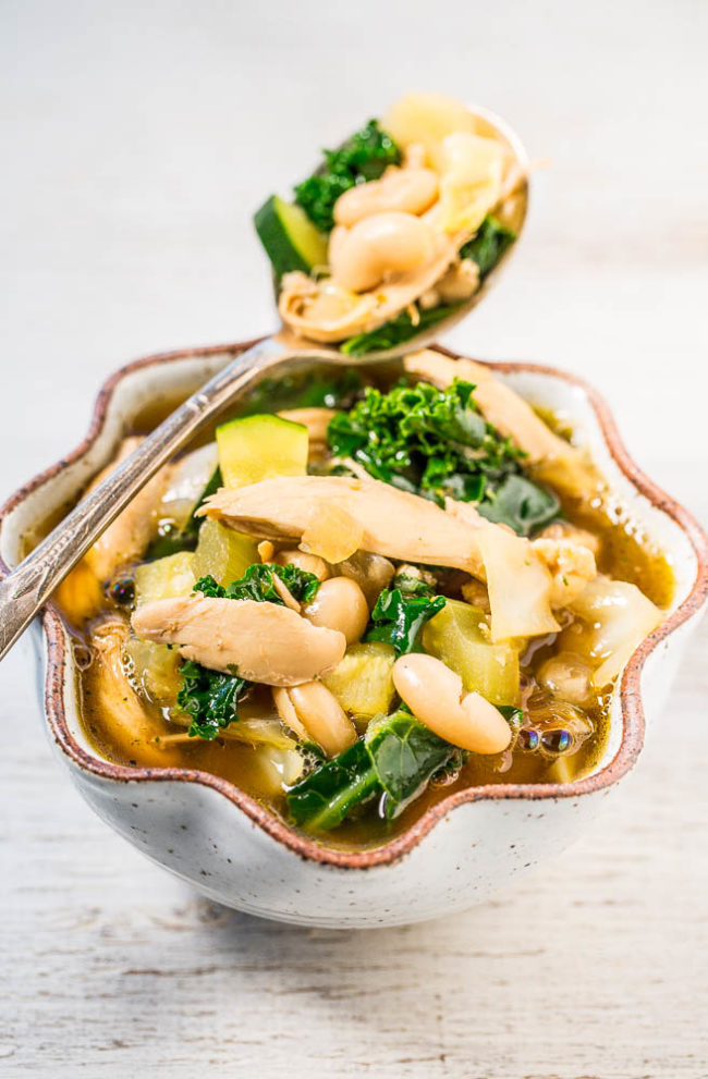A white bowl and spoonful of Easy 30-Minute Kale, White Bean, and Chicken Soup 
