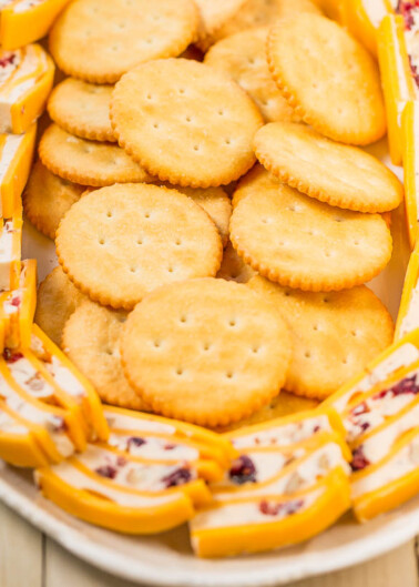 A plate of assorted cheese slices and round crackers.
