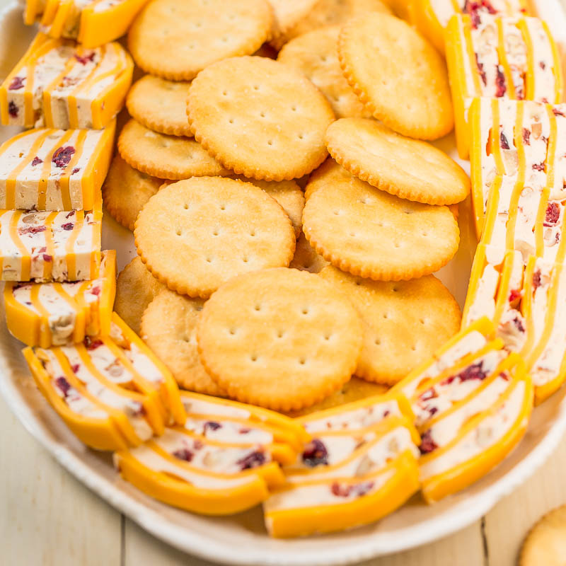 A plate of assorted cheese slices and round crackers.
