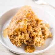A slice of moist cake with caramel sauce on a white plate.