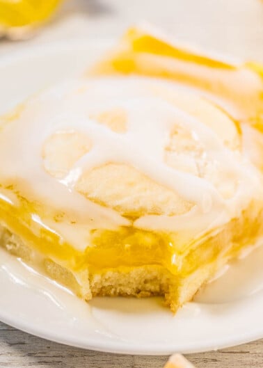 A slice of lemon cake with icing on a white plate.