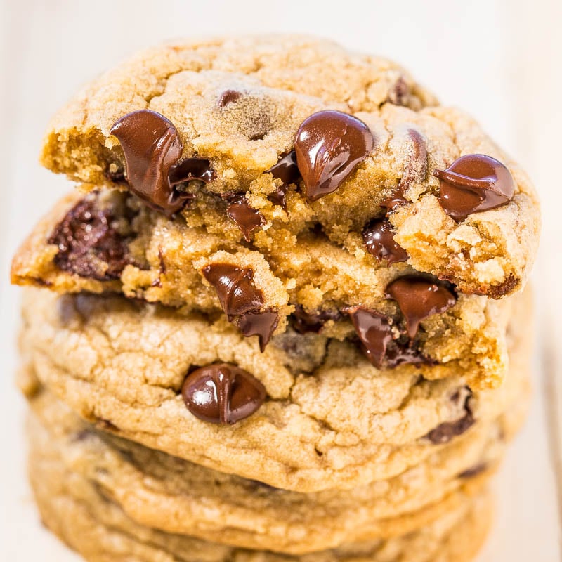 A stack of three chocolate chip cookies with visible gooey chocolate pieces.