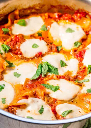 Cheesy baked pasta with tomato sauce and fresh basil in a pan.