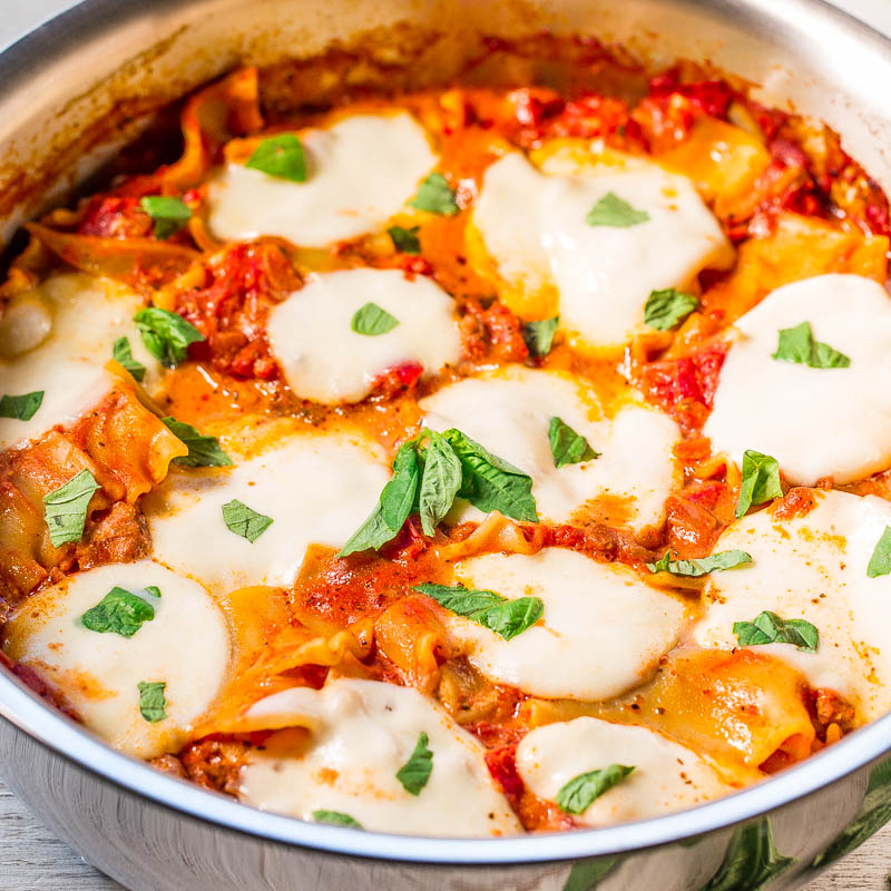 Cheesy baked pasta with tomato sauce and fresh basil in a pan.