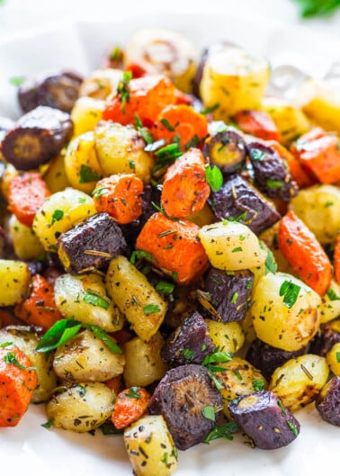 A plate of roasted colorful mixed potatoes garnished with herbs.