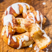 Cinnamon roll with white icing on a wooden surface.