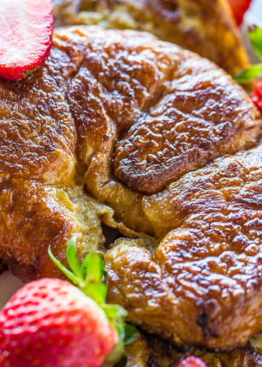 Golden-brown french toast garnished with fresh strawberries.