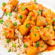 A plate of savory chicken and pineapple served over rice, garnished with fresh herbs.