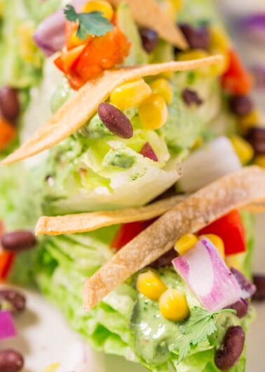 Close-up of a colorful avocado salad topped with tortilla chips, beans, and corn.