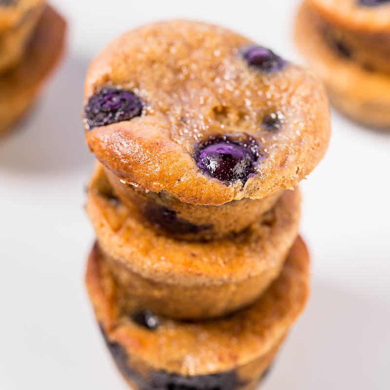 A stack of blueberry muffins with a close-up view on the top one.