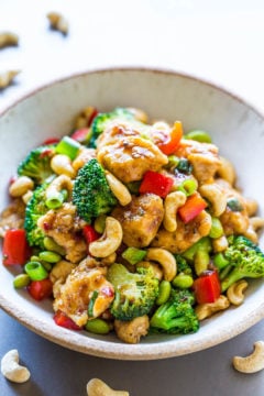 A bowl of stir-fried chicken with broccoli, cashews, and bell peppers.