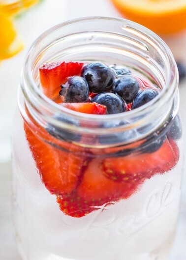 Fresh strawberries and blueberries in a glass jar.