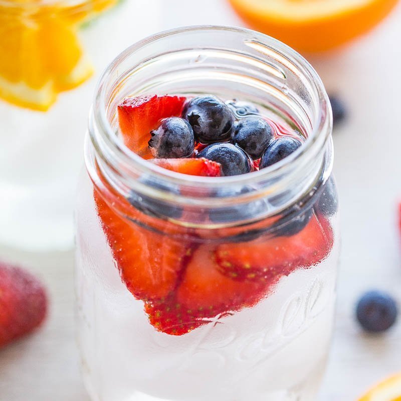 Fresh strawberries and blueberries in a glass jar.