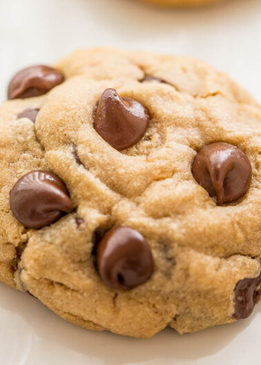 Freshly baked chocolate chip cookie on a white plate.
