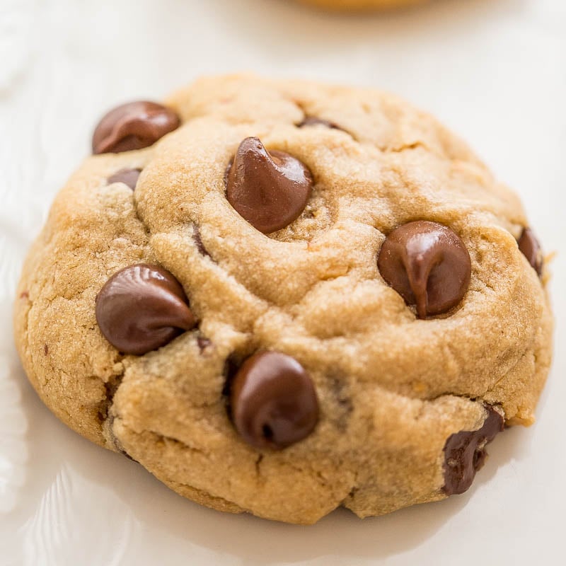 Freshly baked chocolate chip cookie on a white plate.