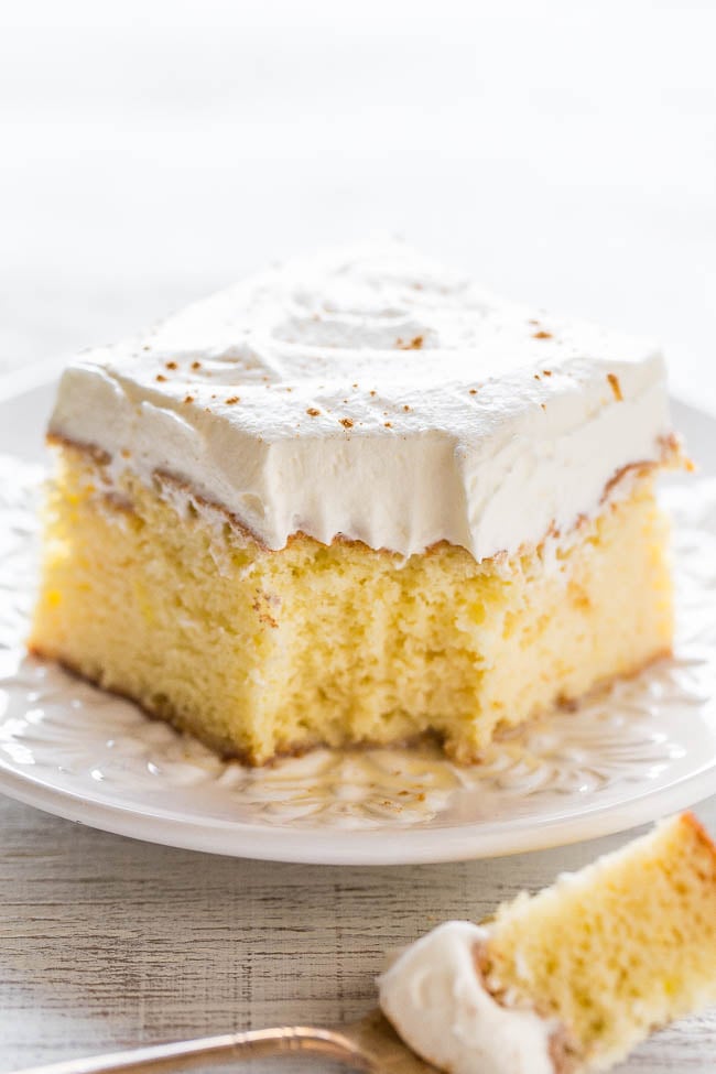 A slice of tres leches sponge cake, with a bite missing. 
