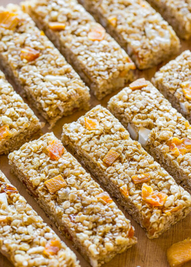 Rows of homemade granola bars with dried fruits on a wooden surface.
