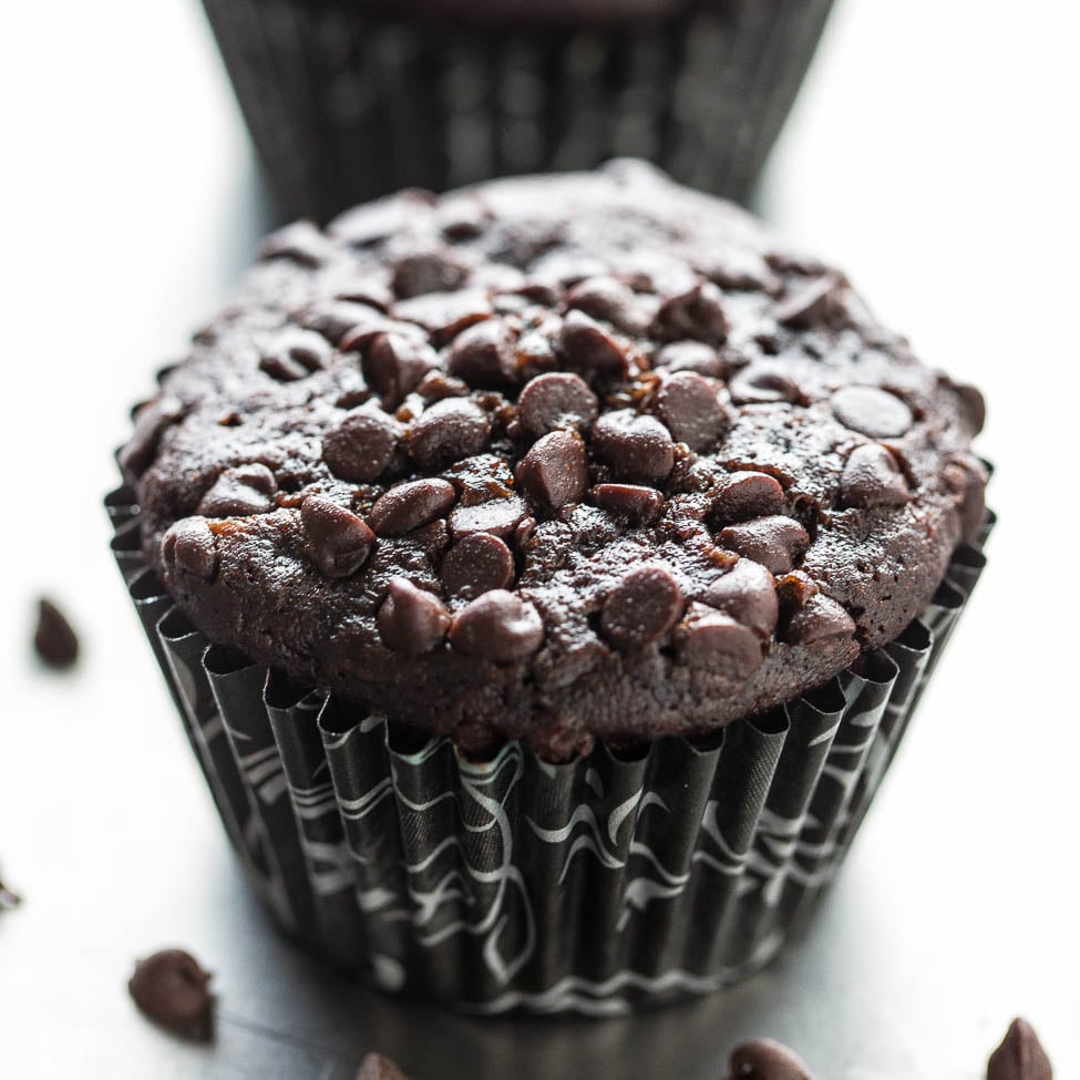 A close-up of a chocolate muffin with chocolate chips on a dark background.