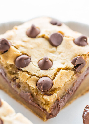 A close-up of a chocolate chip blondie with visible layers of cookie and chocolate.