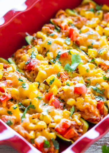Baked enchilada casserole topped with melted cheese and fresh cilantro in a red dish.