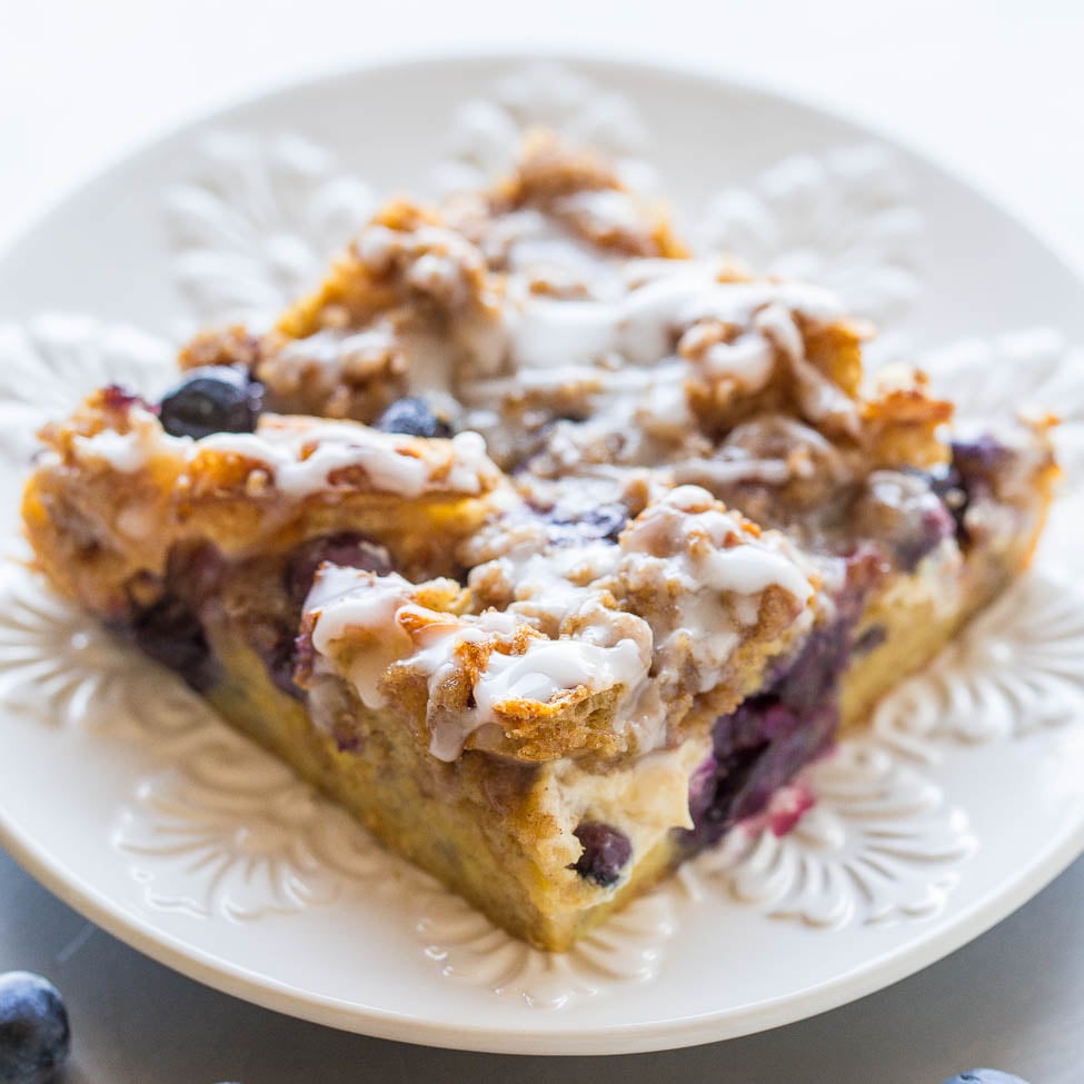 A slice of blueberry coffee cake with icing on a white plate.