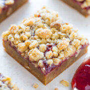 A close-up of a crumb-topped fruit bar on a light surface.