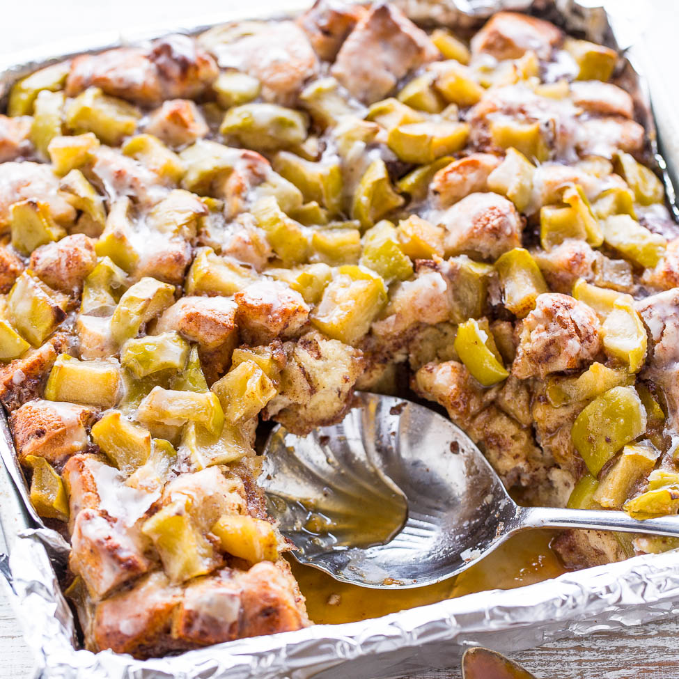 A tray of freshly baked bread pudding with a serving spoon.