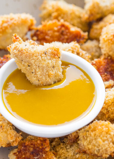 Breaded chicken pieces surrounding a bowl of honey mustard sauce.