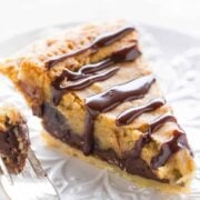 A slice of peanut butter chocolate pie drizzled with chocolate sauce on a white plate.