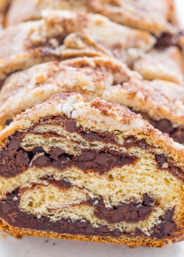 Sliced chocolate babka loaf with swirl pattern on a white surface.