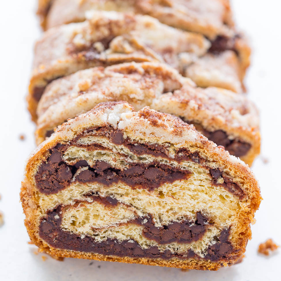 Sliced chocolate babka loaf with swirl pattern on a white surface.