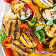 Grilled mixed vegetables seasoned and garnished with basil leaves.