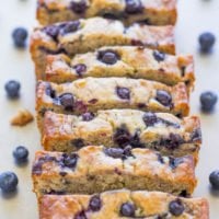 Sliced blueberry loaf cake with berries scattered around.