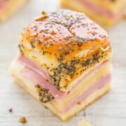 A close-up of a poppy seed-topped pastry with layers of ham and cheese.
