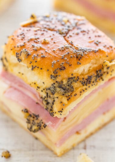A close-up of a poppy seed-topped pastry with layers of ham and cheese.
