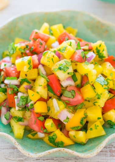 A colorful bowl of mango salsa with diced tomatoes, onions, and herbs.