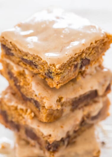 A stack of three frosted blondies on a wooden surface.