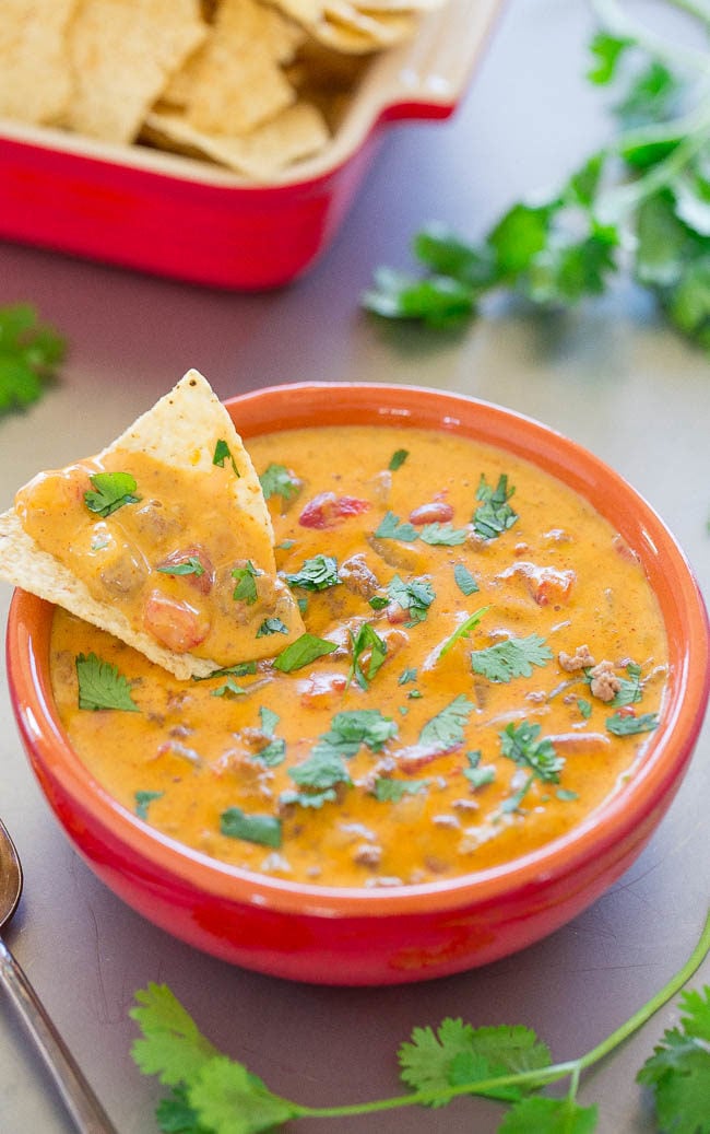 Overhead shot of beef queso dip in a red bowl