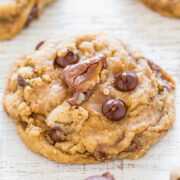 A close-up of a chocolate chip cookie with melted chocolate chips and pecans.