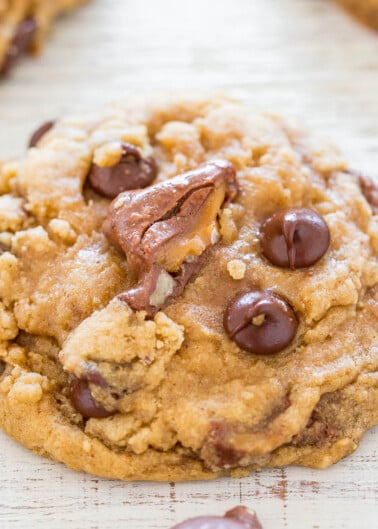 A close-up of a chocolate chip cookie with melted chocolate chips and pecans.
