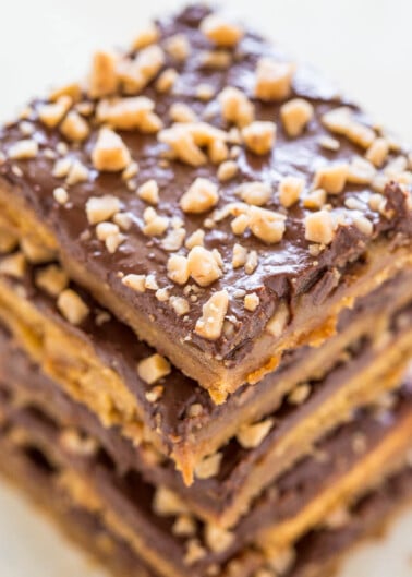 A stack of chocolate caramel squares topped with chopped nuts.