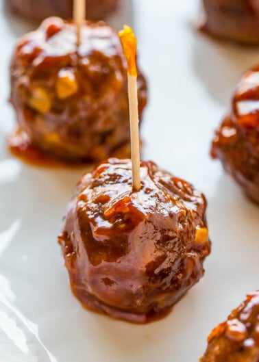 Barbecue sauce glazed meatballs on a plate, served with toothpicks.