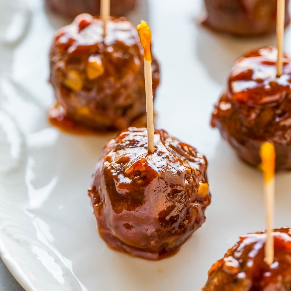 Barbecue sauce glazed meatballs on a plate, served with toothpicks.