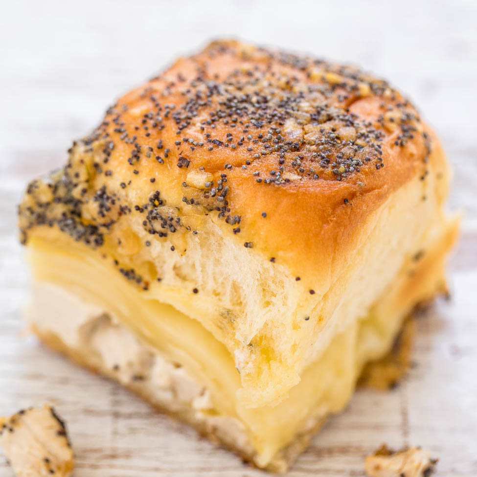 A slice of cheese and poppy seed bread on a wooden surface.