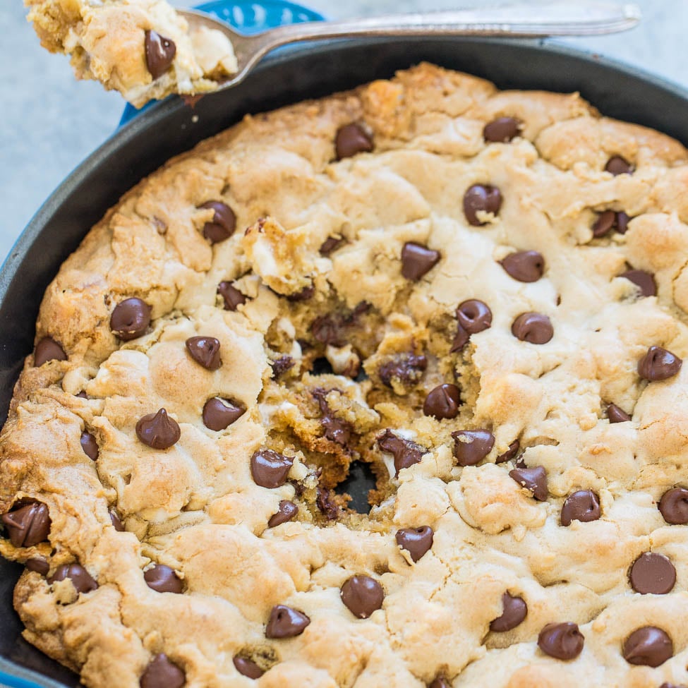 A freshly baked chocolate chip cookie skillet with a slice being lifted out.
