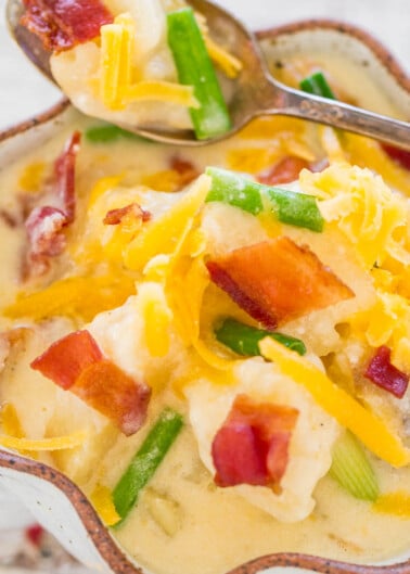 Loaded baked potato soup topped with cheese, bacon, and green onions in a bowl.